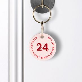 Custom printed leather keyring with a pink texture and bold red lettering, it is attached to a key using silver rings