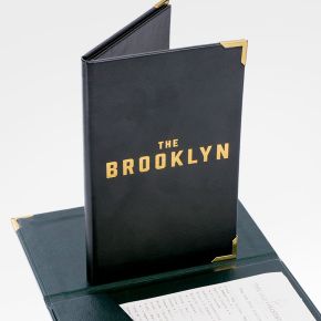 Black leather bill presenter with gold corners shown closed and open, displaying interior receipt pocket.