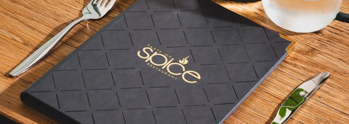 Taste of Spice menu with a gold logo on a wooden table