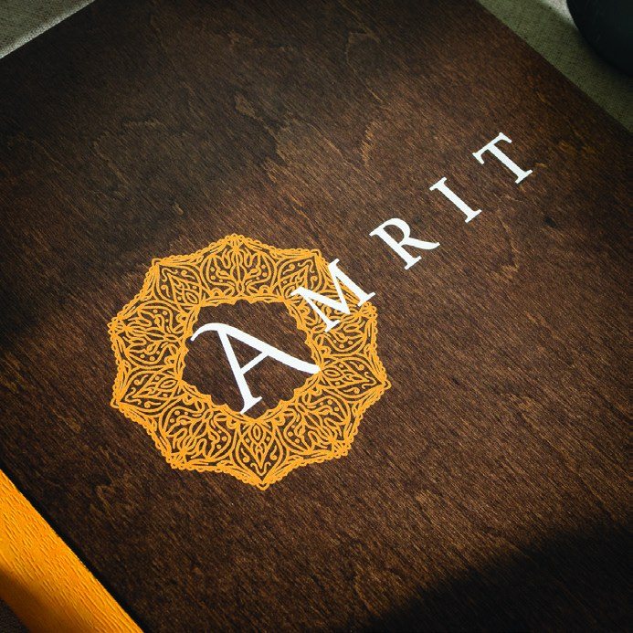 Wooden menu cover with the engraved Amrit logo