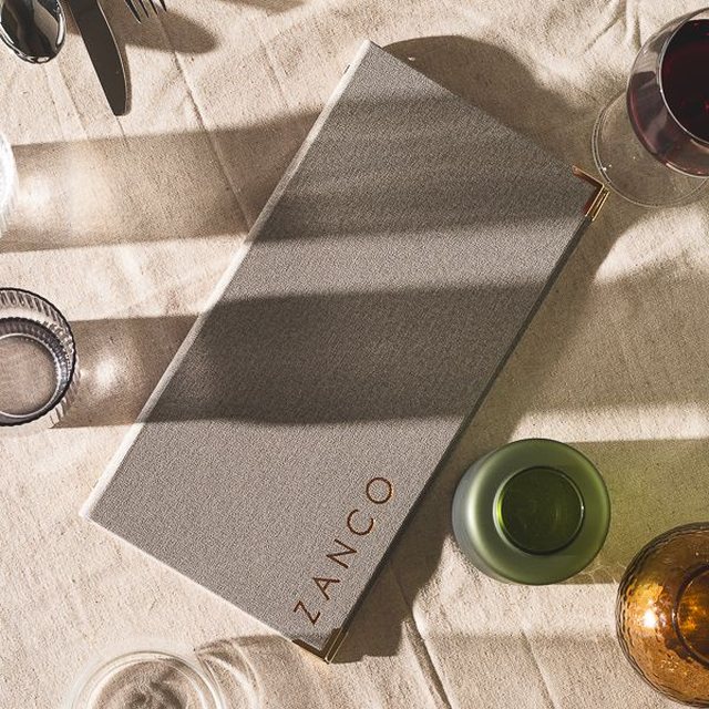 Grey fabric Zanco menu with a copper logo
